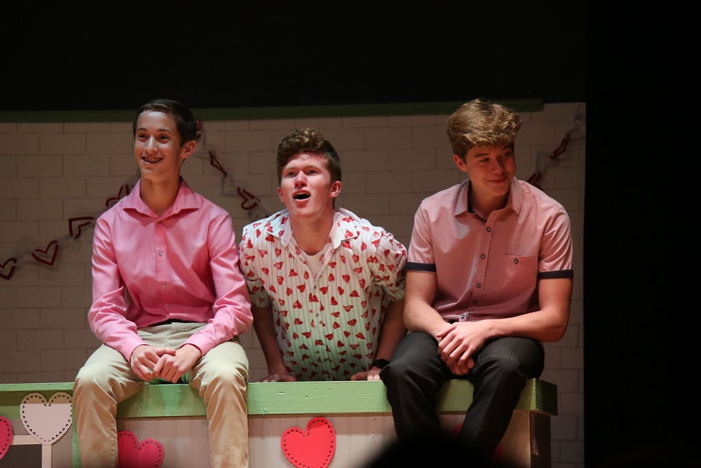 Three male students singing in theater