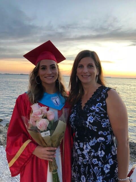 Female student in graduation gown and cap with mother